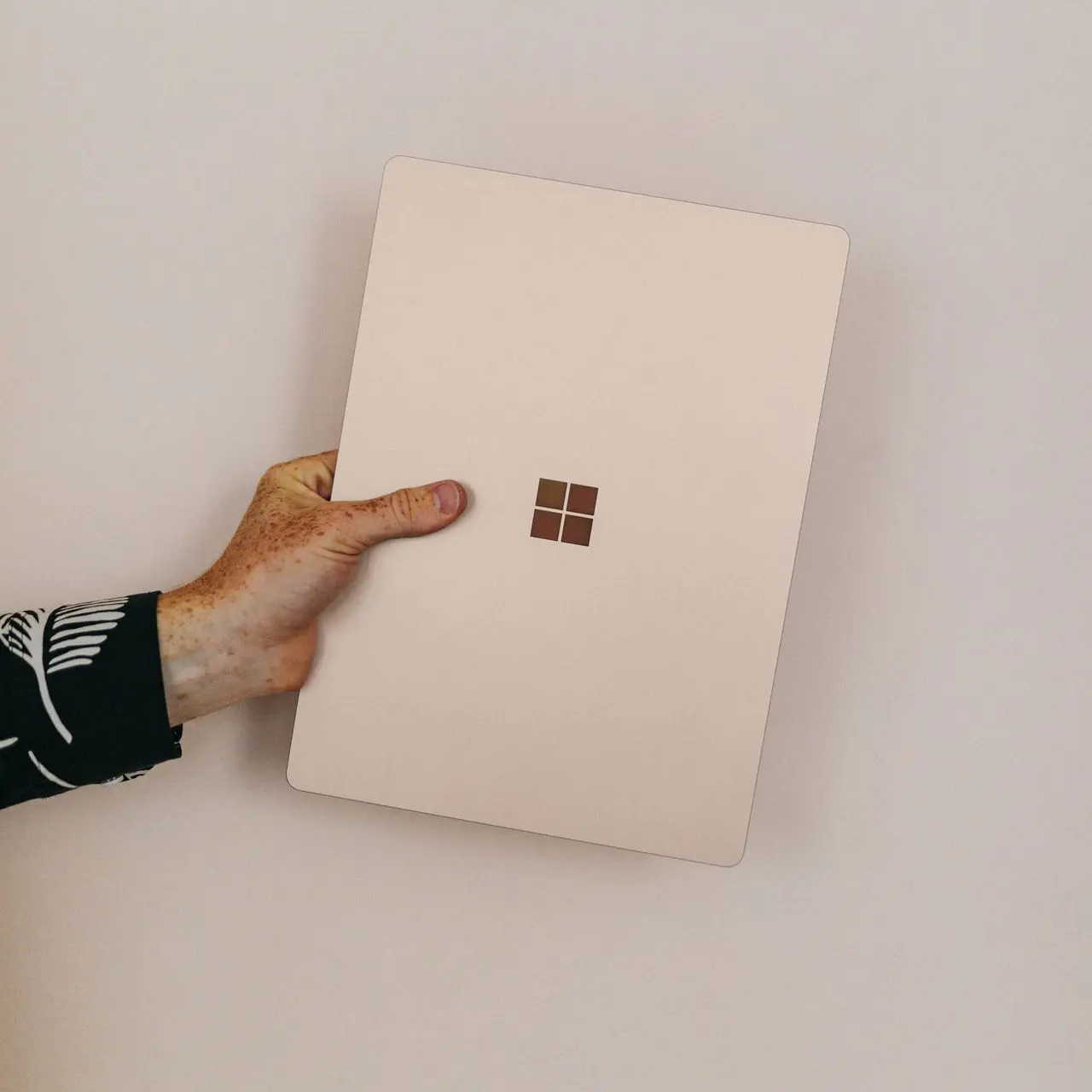 person holding sandstone microsoft Surface laptop laptop